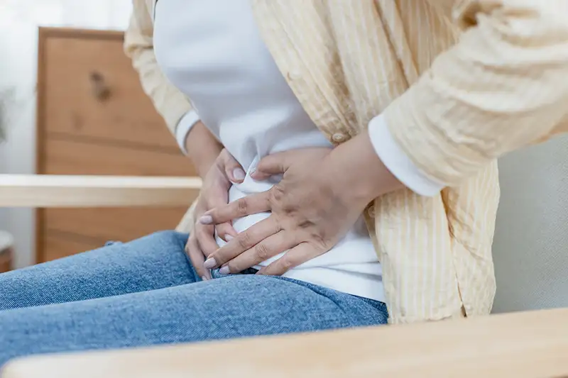 A lady holding her bladder in discomfort due to fecal incontinence.