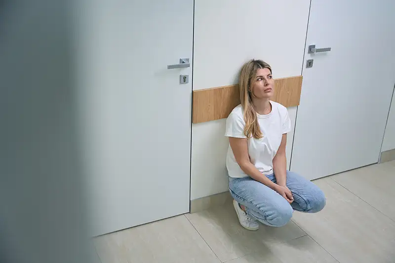 A woman kneeling down urgently waiting for the restroom.